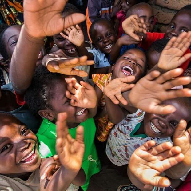 A group of joyful children reaching up toward the camera in Tanzania